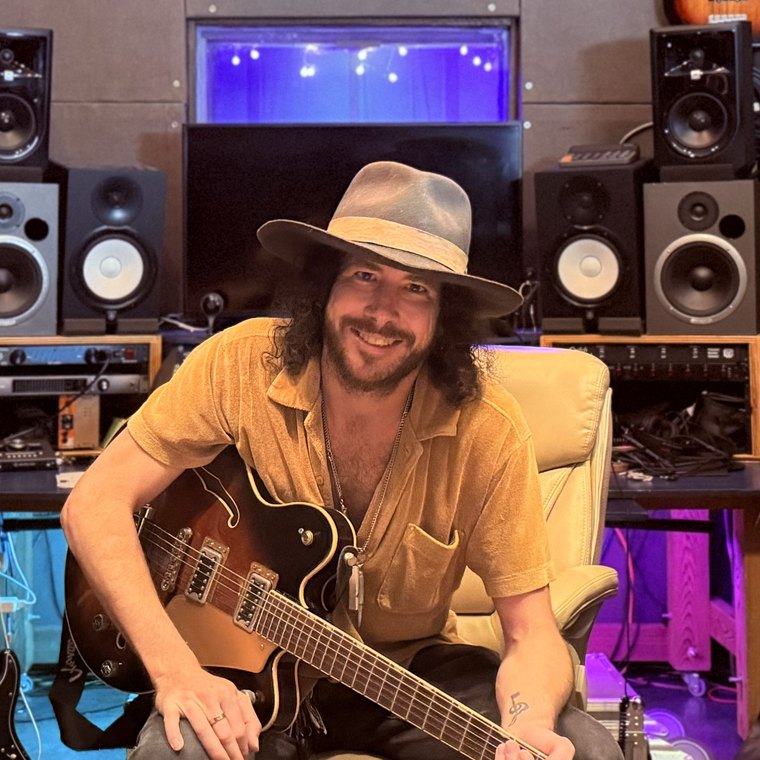 David Click, founder and chief engineer of The Oven ATX, seated with a guitar in the studio